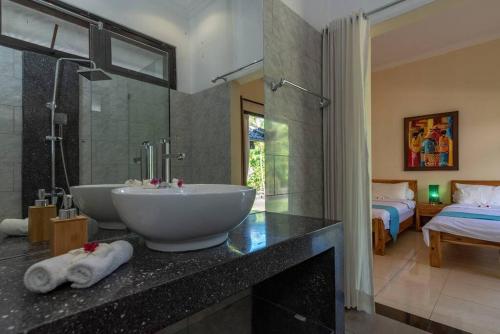 1 cama y baño con lavabo y ducha. en Villa Lovina Beach 1, en Banjar
