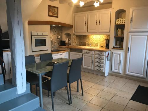 une cuisine avec des armoires blanches et une table et des chaises dans l'établissement Gîte Maison de Sophie, à Saint-Aignan