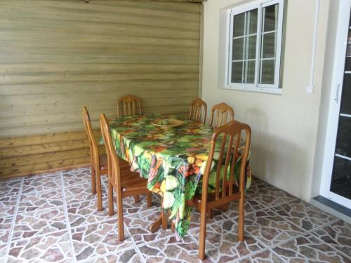 a dining room table with chairs and a tablecloth on it at Les Meublés Les Dauphins in Étang-Salé les Bains