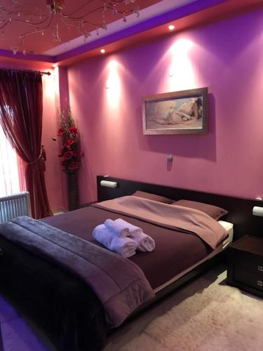a bedroom with purple walls and a bed with towels at Apartament in Aridaia