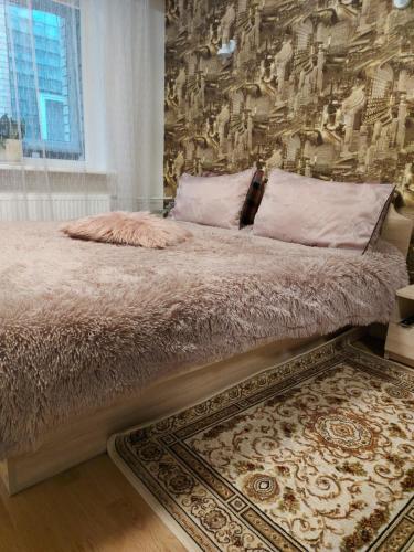 a bedroom with a large bed with a wall at Apartamentai „Kaip namuose“ in Druskininkai