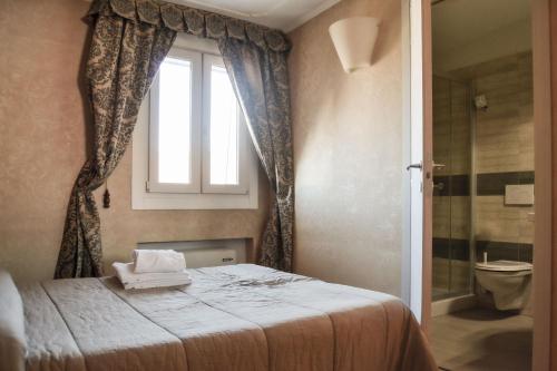 una camera con letto, finestra e servizi igienici di Hotel Domus a Maranello