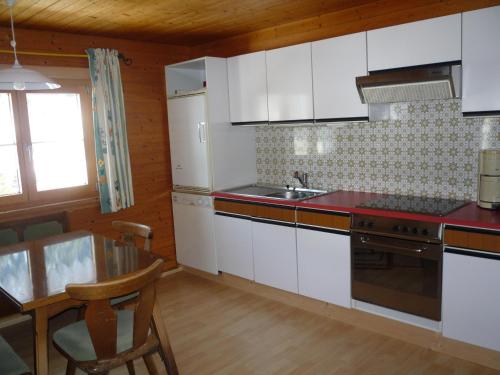 eine Küche mit weißen Schränken, einer Spüle und einem Tisch in der Unterkunft Ferienwohnung Helma in Blons