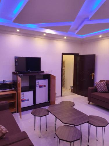 un soggiorno con divano, tavoli e TV di Al Shadi Apartments a Yanbu