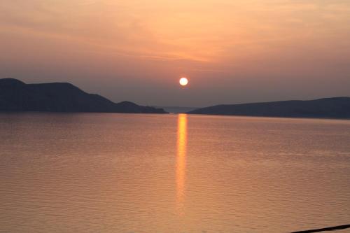 una puesta de sol en el agua con el sol reflejándose en el agua en Apartments Lidija, en Sveti Juraj