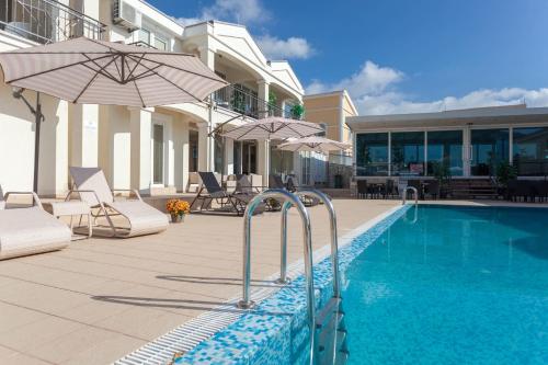 a swimming pool with umbrellas and chairs next to a house at Spa Resort Luxury Apartments in Budva