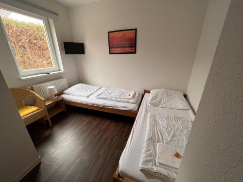 two beds in a small room with a window at Leuchtfeuer Fewo "Chris" in Börgerende-Rethwisch