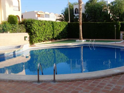 una piscina azul con palmeras y arbustos en Charming Apartment in Mazarrón with Sea View, 110 m², en Mazarrón