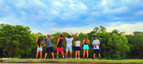 a group of people standing in the grass with their hands in the air at Hasthi Safari Cottage in Udawalawe