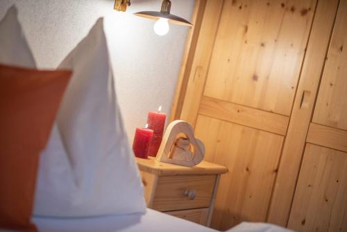 a bedroom with a bed with a mirror and two red candles at Oberglarzhof App Kirsch in Villnoss