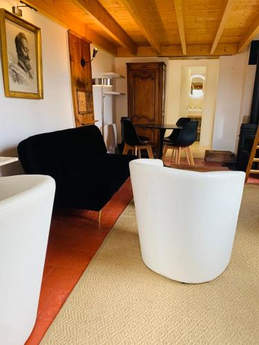 a living room with a black couch and chairs at Le petit Chapitre in Pinterville