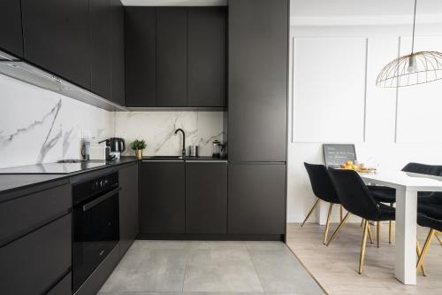 a kitchen with black cabinets and a white table at Old Town Heart IX Luxury - Przyokopowa in Warsaw