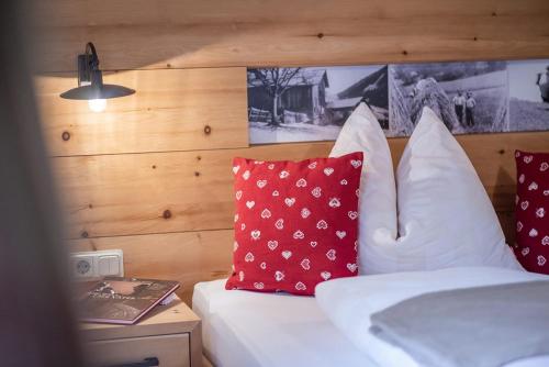 Schlafzimmer mit einem Bett mit roten und weißen Kissen in der Unterkunft Oberglarzhof App Zirbel in Villnöß