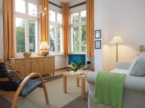 sala de estar con sofá, silla y ventanas en Villa Bismarckshöhe Wohnung Gertrud, en Ahlbeck