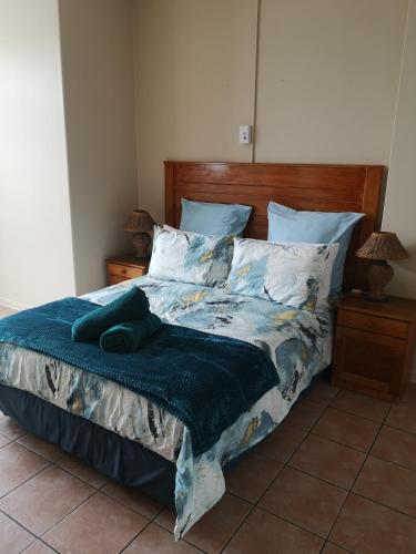a bed with a blue comforter and pillows at 106 Umdloti Resort in Umdloti