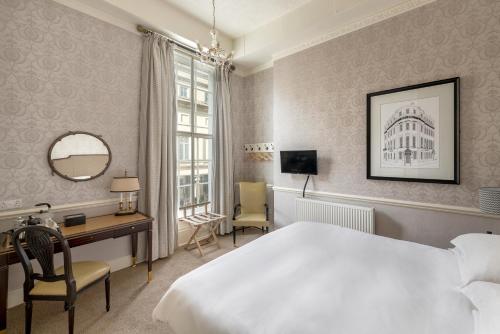 Royal Hotel في باث: غرفة في الفندق بها سرير ومكتب ومرآة