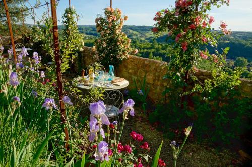 a table in a garden with flowers at La Dommerie-Gite de charme in Domme