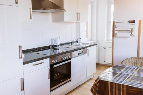 a white kitchen with a sink and a stove at Ferienwohnung an der Berliner Seenkette in Schwerin