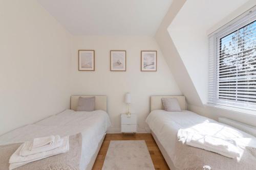 two beds in a white room with a window at Spacious One Bed loft Apartment in Birchanger