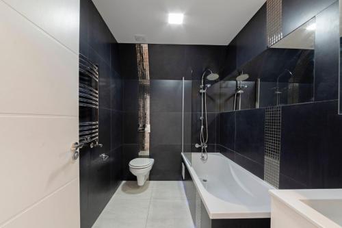 a bathroom with a tub and a toilet and a sink at Spacious One Bed loft Apartment in Birchanger