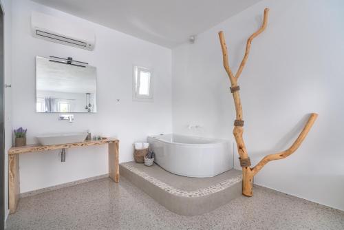 La salle de bains est pourvue d'une baignoire blanche et d'un arbre. dans l'établissement IL Vento Suites, à Mykonos