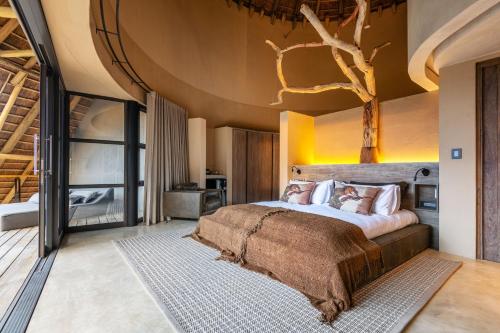 a bedroom with a large bed with a tree on the ceiling at TimBila Private Villa in Omaruru