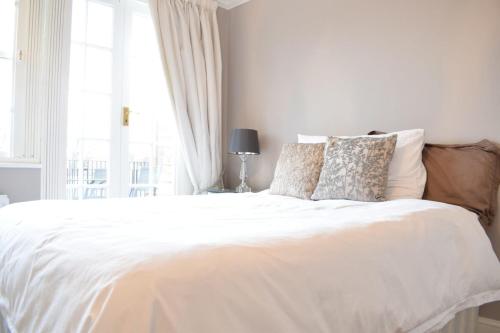 a bedroom with a white bed with a window at Spacious and Stylish 1 Bedroom Flat near Chelsea in London