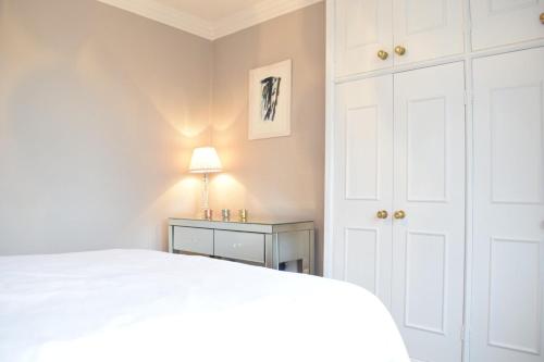 a bedroom with a white bed and a night stand at Spacious and Stylish 1 Bedroom Flat near Chelsea in London
