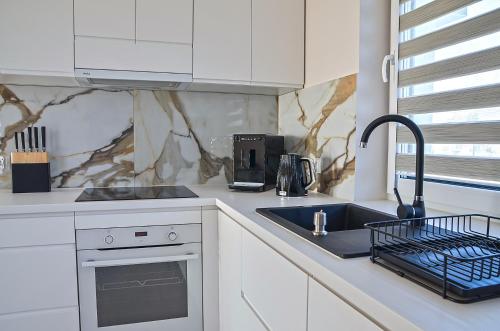 a white kitchen with a sink and a counter top at Domy na polanie- Szarotka in Wolany