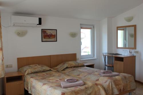 a bedroom with a bed with two towels on it at Hotel Radik in Sozopol