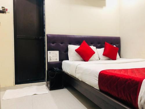 a bedroom with a bed with red pillows on it at Hotel Guestinn Residency in Mumbai
