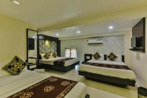a hotel room with two beds and a television at Hotel Guestinn Residency in Mumbai