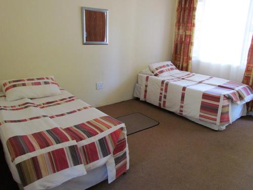two beds sitting in a room with a window at Aruka in Bela-Bela