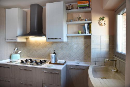 cocina con armarios blancos, fogones y fregadero en Locazione Turistica Arcobaleno "Appartamento Superior" en Roccavivara