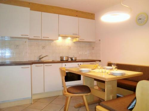 uma cozinha com armários brancos e uma mesa de madeira em Schöne Ferienwohnung em Siusi