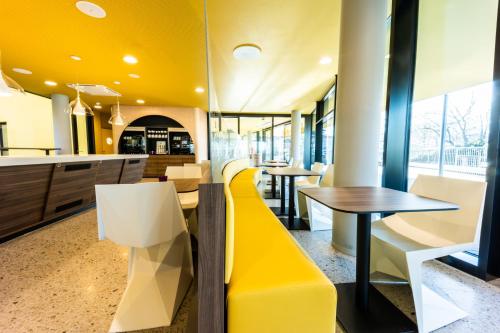 a restaurant with yellow and white chairs and tables at Prize by Radisson, Bonn City in Bonn