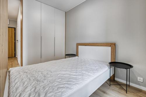 ein Schlafzimmer mit einem weißen Bett und zwei schwarzen Hockern in der Unterkunft Primo III by LookAp Centrum Dworzec Fabryczny FV in Łódź