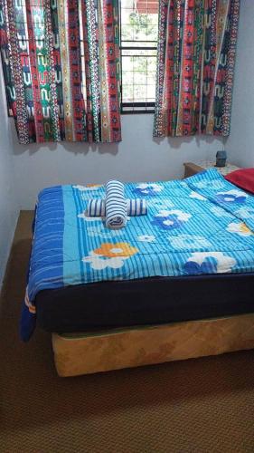 a bed with a blue quilt with a stuffed animal on it at Cool Living at GVR Landed Unit in Genting Highlands