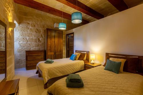 - une chambre avec 2 lits et un mur en pierre dans l'établissement Andrea Luxury Holiday Farmhouse, à Munxar