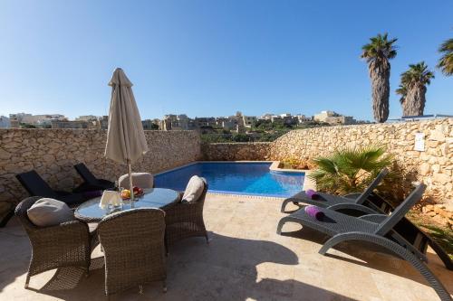 a patio with a table and chairs and a pool at Stunning 4 bedrooms House with views in Gozo in Munxar