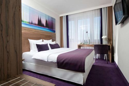 a bedroom with a bed and a desk and a television at Wyndham K&ouml;ln in Cologne