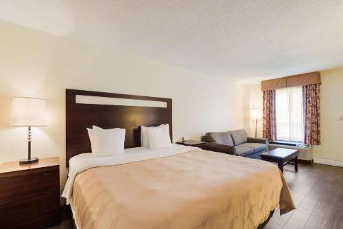 a hotel room with a large bed and a chair at Quality Inn & Suites Conference Center Statesboro Historic District in Statesboro