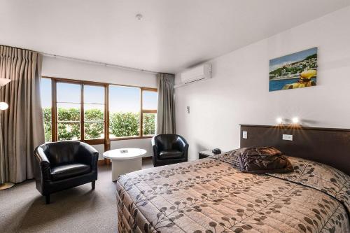 a hotel room with a bed and two chairs at Quality Hotel The Angus in Lower Hutt