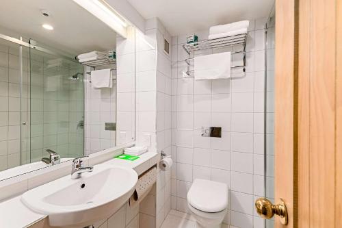 a white bathroom with a sink and a toilet at The Angus Hotel in Lower Hutt