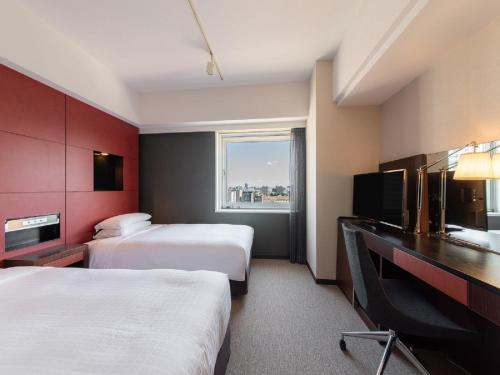 a hotel room with two beds and a television at Hotel Vista Sapporo Nakajima Koen in Sapporo