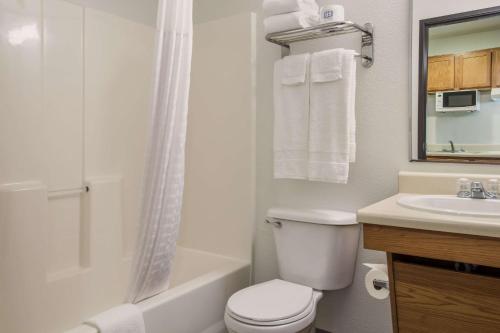 a white bathroom with a toilet and a sink at WoodSpring Suites Houston La Porte in La Porte