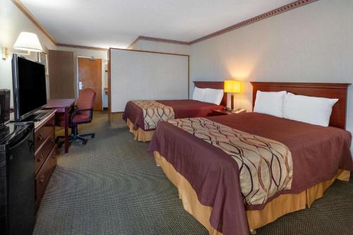 a hotel room with two beds and a flat screen tv at Travelodge by Wyndham Cleveland Airport in Brook Park