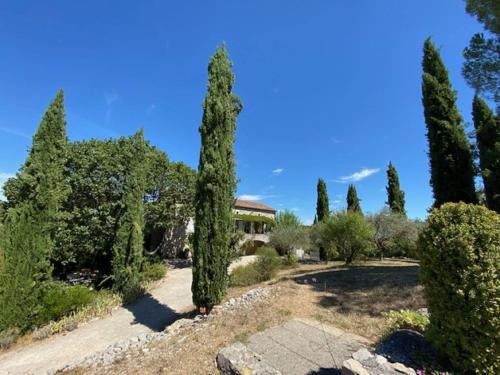 un jardín con árboles y una casa al fondo en Superb villa with private pool, en Banne