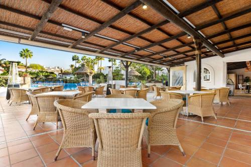 a patio with tables and chairs and a pool at Wyndham Residences Golf del Sur in San Miguel de Abona