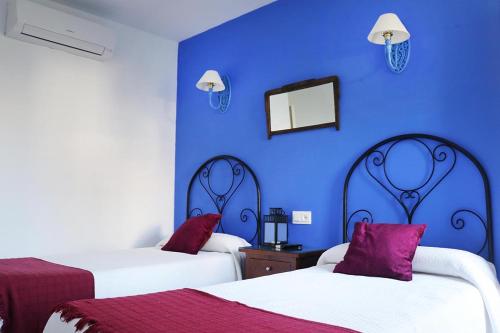 Habitación azul con 2 camas y espejo. en Hostal Arco Plaza, en Mojácar
